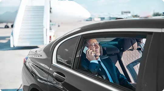 Business traveler on phone in luxury car near private jet at Florida airport